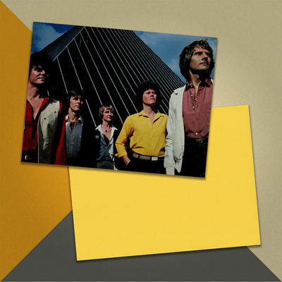 Photo of a 11” x 8.5” notebook cover made from an upcycled Air Supply "Lost in Love" album sleeve and the back cover with yellow cardstock on an orange, cream and grey background.