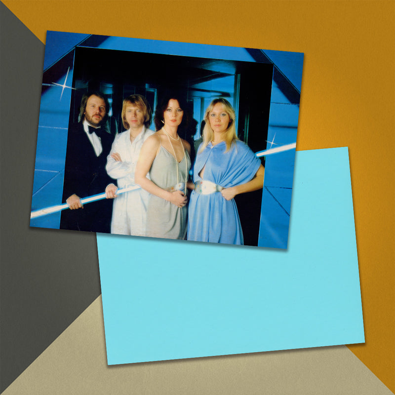 Photo of a 11” x 8.5” notebook cover made from an upcycled ABBA "Voulez-Vous!" album sleeve and the back cover with light blue cardstock on an orange, cream and grey background.