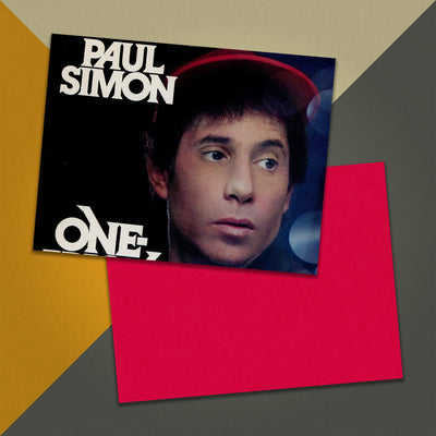 Photo of a 11” x 8.5” notebook cover made from an upcycled Paul Simon “One Trick Pony” album sleeve and the back cover with red cardstock on an orange, cream and grey background.