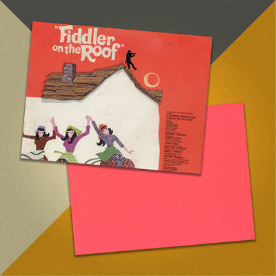 Photo of a 11” x 8.5” notebook cover made from an upcycled John Williams / Isaac Stern “Fiddler On The Roof (Original Motion Picture Soundtrack)” album sleeve and the back cover with coral cardstock on an orange, cream and grey background.