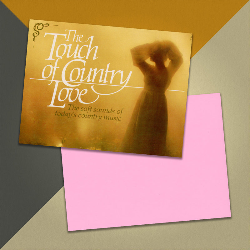 Photo of a 11” x 8.5” notebook cover made from an upcycled Various “The Touch Of Country Love” album sleeve and the back cover with pink cardstock on an orange, cream and grey background.