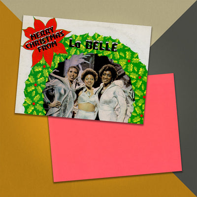 Photo of a 11” x 8.5” notebook cover made from an upcycled LaBelle & The Bluebelles “Merry Christmas From LaBelle & The Bluebelles” album sleeve and the back cover with coral cardstock on an orange, cream and grey background.