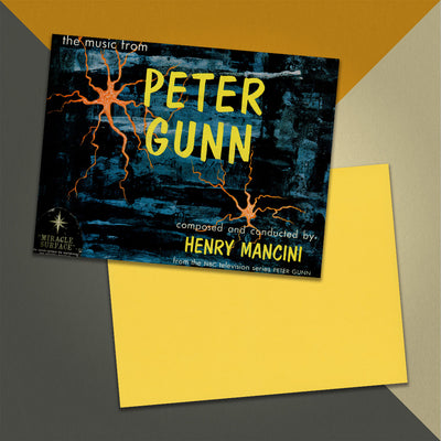 Photo of a 11” x 8.5” notebook cover made from an upcycled Henry Mancini “The Music From Peter Gunn” album sleeve and the back cover with yellow cardstock on an orange, cream and grey background.