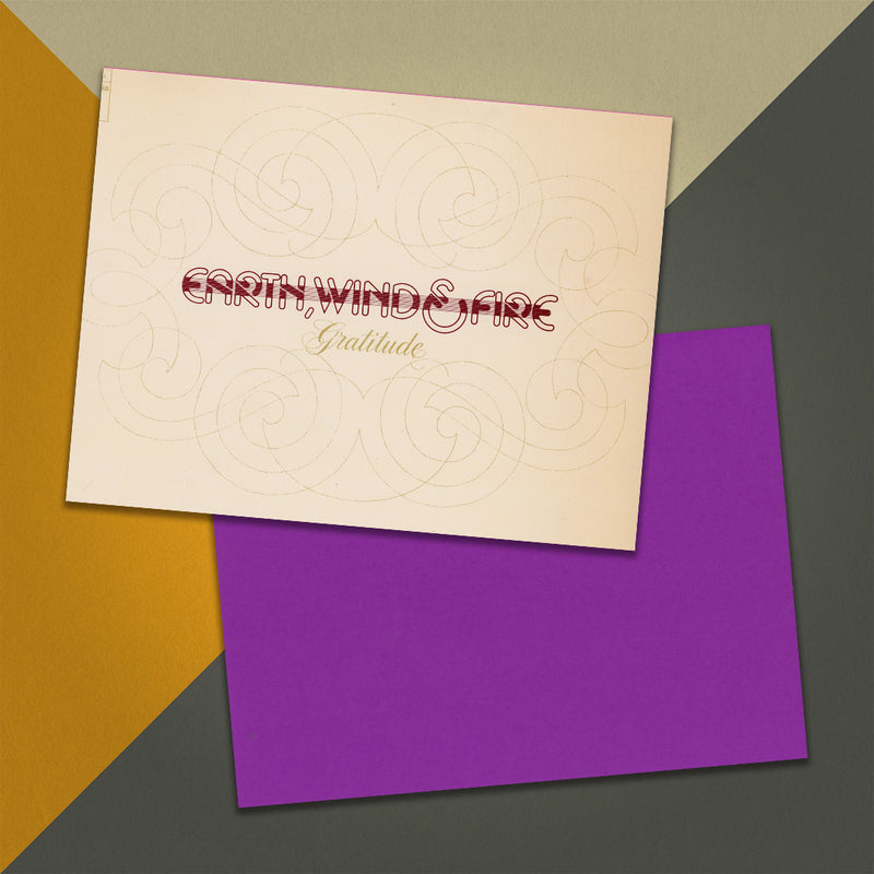 Photo of a 11” x 8.5” notebook cover made from an upcycled Earth, Wind & Fire “Gratitude” album sleeve and the back cover with purple cardstock on an orange, cream and grey background.