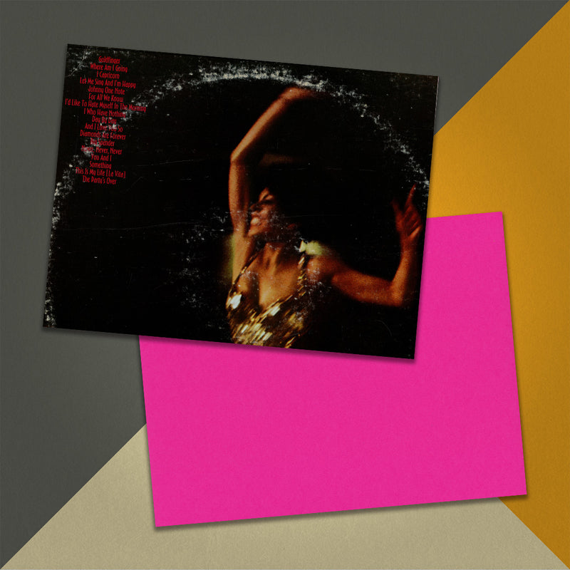 Photo of a 11” x 8.5” notebook cover made from an upcycled Shirley Bassey “Live At Carnegie Hall” album sleeve and the back cover with hot pink cardstock on an orange, cream and grey background.