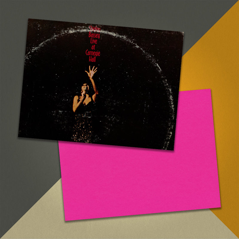 Photo of a 11” x 8.5” notebook cover made from an upcycled Shirley Bassey “Live At Carnegie Hall” album sleeve and the back cover with hot pink cardstock on an orange, cream and grey background.