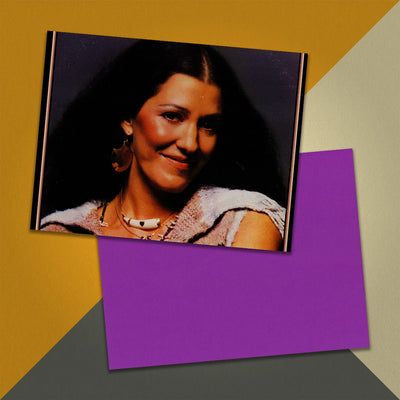 Photo of a 11” x 8.5” notebook cover made from an upcycled Rita Coolidge “Anytime... Anywhere” album sleeve and the back cover with purple cardstock on an orange, cream and grey background.