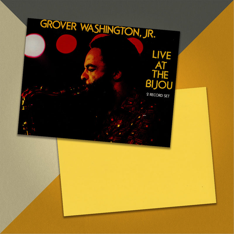 Photo of a 11” x 8.5” notebook cover made from an upcycled Grover Washington, Jr “Live At The Bijou” album sleeve and the back cover with yellow cardstock on an orange, cream and grey background.