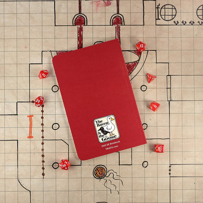 The bright red back cover of the barbarian notebook with "The Raven and the Goose" logo on the bottom. The notebook sits on a grid map surrounded by dice.