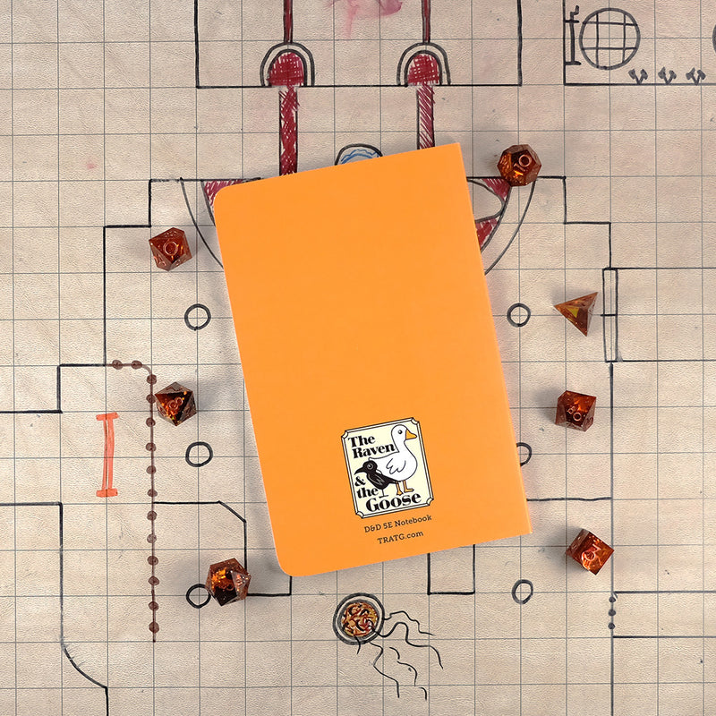 The bright orange back cover of the bard notebook with "The Raven and the Goose" logo on the bottom. The notebook sits on a grid map surrounded by dice.