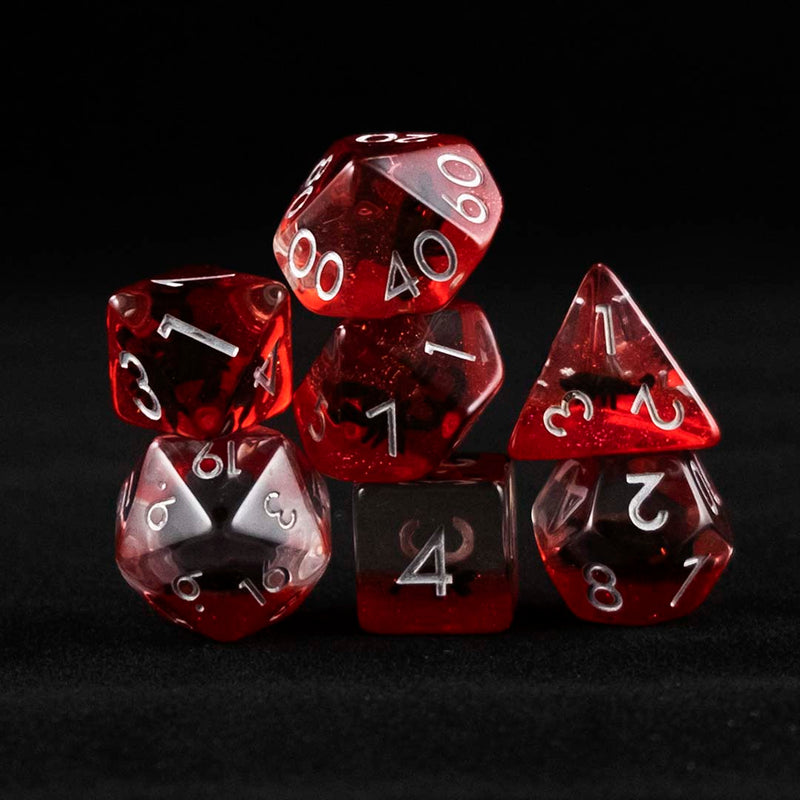 A set of clear and red polyhedral dice with black scorpion inclusions on a black background.