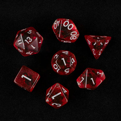 A set of clear and red polyhedral dice with black scorpion inclusions from above on a black background.