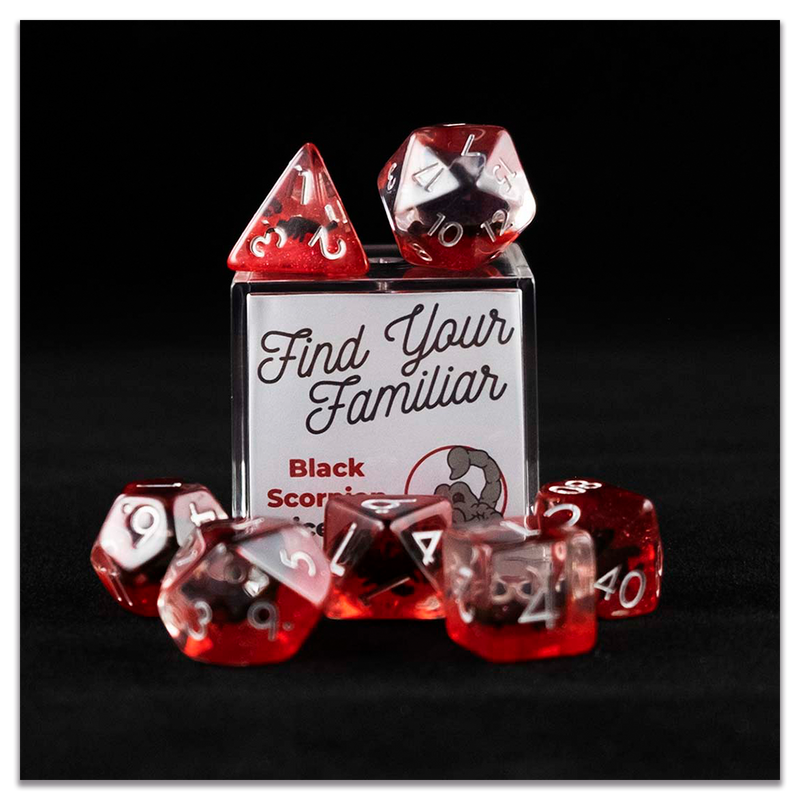 A set of clear and red polyhedral dice with black scorpion inclusions sitting on top and around a small acrylic box with the words "Find Your Familiar" and "Black Scorpion Dice Set" on a transparent background.