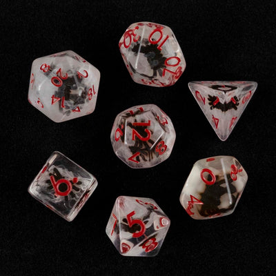 A set of clear and cloudy polyhedral dice with black spider inclusions from above on a black background.