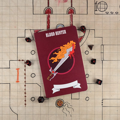 The front cover of a large blood hunter notebook with a dark red cover and an illustration of a flaming sword with blood on the tip. The notebook sits on a grid map surrounded by dice.