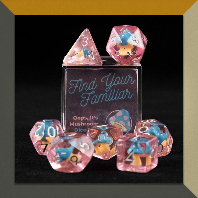 A set of pink polyhedral dice with blue and pink cap mushroom inclusions sitting on top and around a small acrylic box with the words "Find Your Familiar" and "Oops, It&