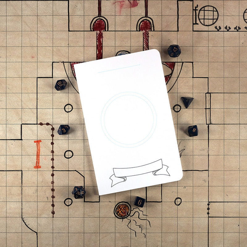 The front cover of a large DIY character notebook with a white cover and an illustration of a two blue circles for creating your own character icon. The notebook sits on a grid map surrounded by dice.