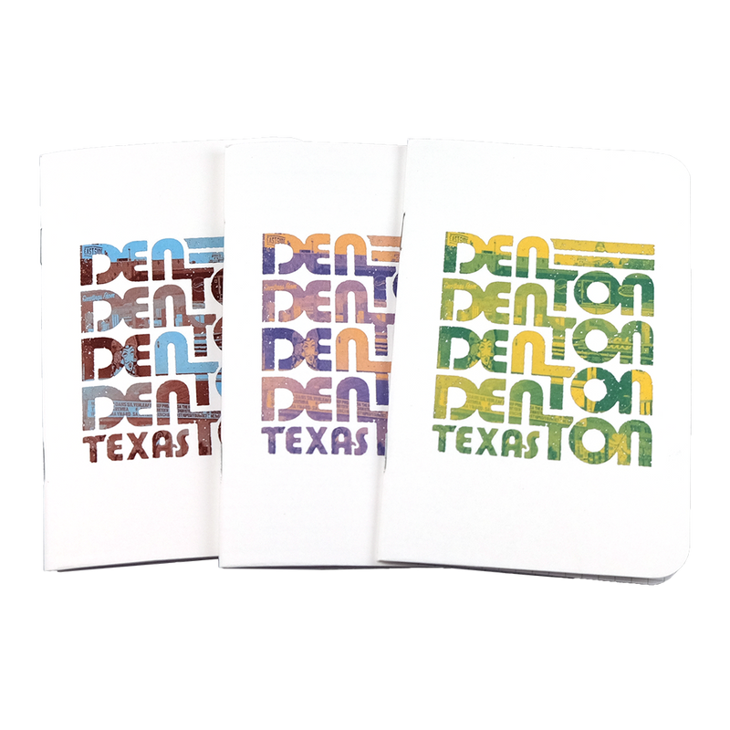 The front covers of three Denton notebooks with the word "Denton" stacked four times and the word "Texas" underneath in maroon and blue, purple and orange, and green and yellow duotones. The notebooks are on a transparent background.