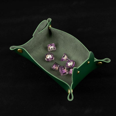 Photo of a green cat shaped dice tray from above with a set of dice inside on a black background.