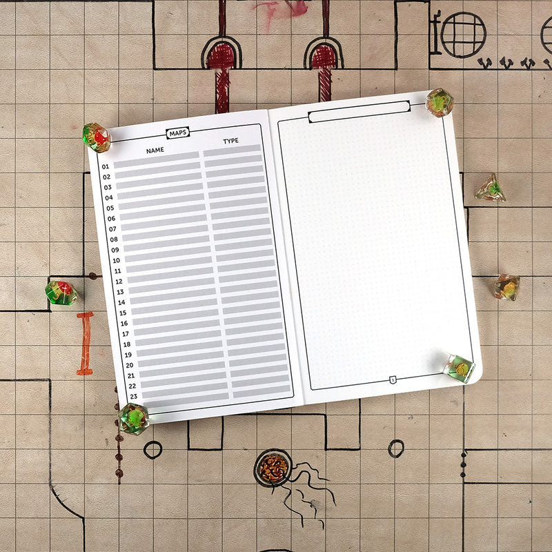 Pages of a Maps notebook with a blank table of contents on the left and a blank reticle grid with a border on the right on a grid map surrounded by dice.