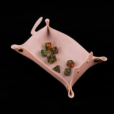 Photo of a pink cat shaped dice tray from above with a set of dice inside on a black background.