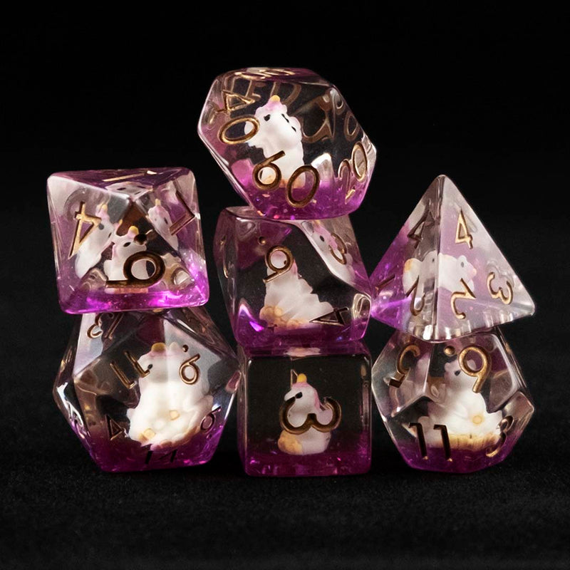 A set of clear and purple polyhedral dice with pink unicorn inclusions on a black background.