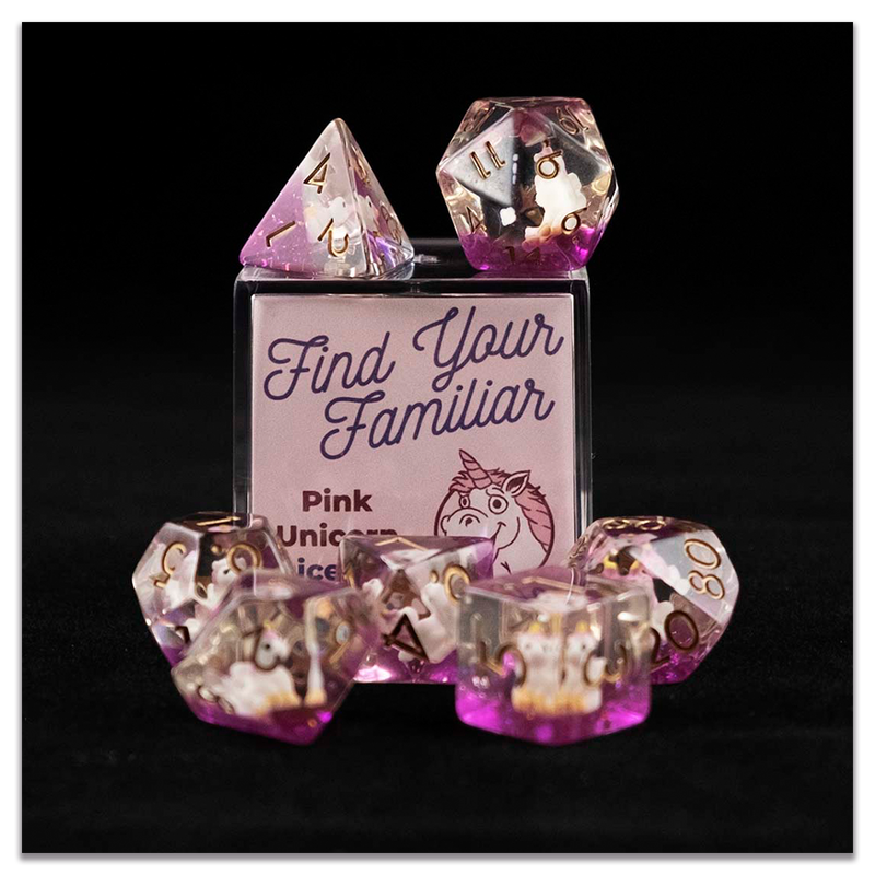 A set of clear and purple polyhedral dice with pink unicorn inclusions sitting on top and around a small acrylic box with the words "Find Your Familiar" and "Pink Unicorn Dice Set" on a transparent background.