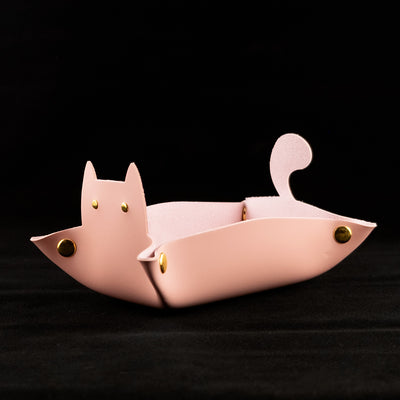 Photo of a pink cat shaped dice tray facing left on a black background.