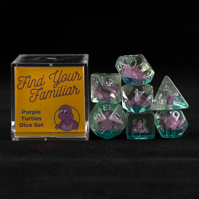 A set of clear green polyhedral dice with purple turtle inclusions sitting to the right of a small acrylic box with the words "Find Your Familiar" and "Purple Turtles Dice Set" on a black background.