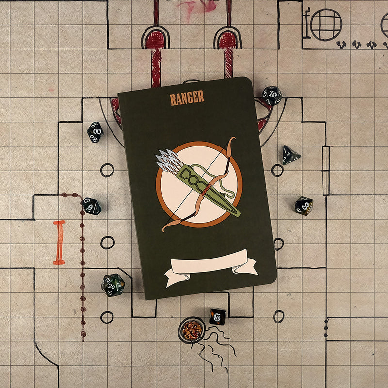 The front cover of a large ranger notebook with a dark green cover and an illustration of a bow and a quiver of arrows. The notebook sits on a grid map surrounded by dice.