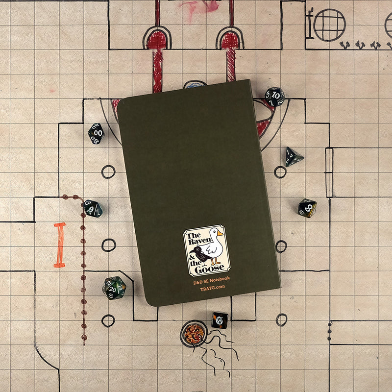 The dark green back cover of the ranger notebook with "The Raven and the Goose" logo on the bottom. The notebook sits on a grid map surrounded by dice.