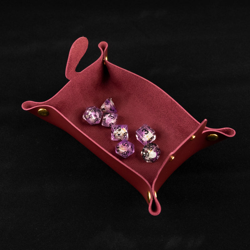 Photo of a red cat shaped dice tray from above with a set of dice inside on a black background.