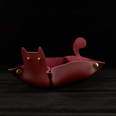 Photo of a red cat shaped dice tray facing left on a black background.