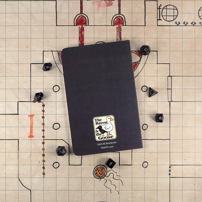 The dark gray back cover of the rogue notebook with "The Raven and the Goose" logo on the bottom. The notebook sits on a grid map surrounded by dice.