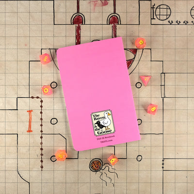 The light pink back cover of the sorcerer notebook with "The Raven and the Goose" logo on the bottom. The notebook sits on a grid map surrounded by dice.