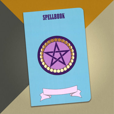 A large spellbook notebook with a bright blue cover and an illustration of a purple pentacle surrounded by yellow circles with shadows for the different phases of the moon, on a orange, cream and grey background.