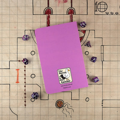 The bright purple back cover of the warlock notebook with "The Raven and the Goose" logo on the bottom. The notebook sits on a grid map surrounded by dice.