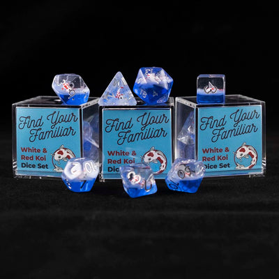 A set of clear and blue polyhedral dice with red and white koi inclusions sitting on top and around a three small acrylic boxes with the words "Find Your Familiar" and "Red & White Koi Dice Set" on a black background.