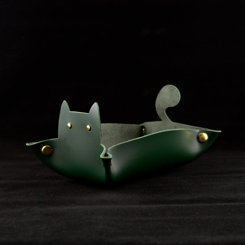 Photo of a green cat shaped dice tray facing left on a black background.