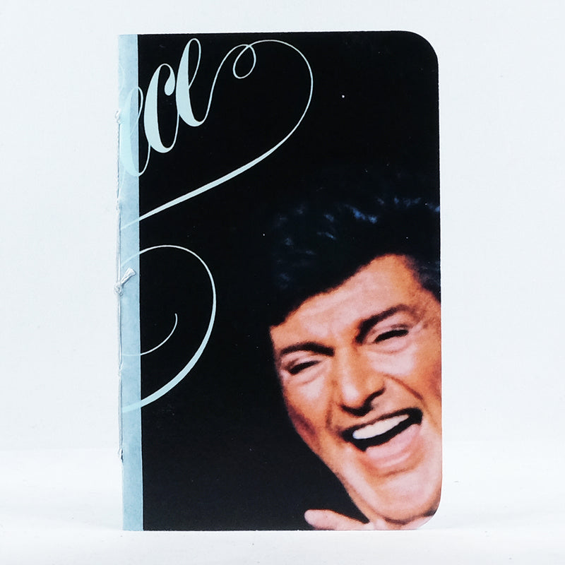 Photo of the front cover of a pocket notebook made from an upcycled Liberace "Masterpiece: Liberace Plays The World&