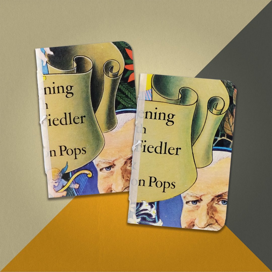 Photo of two pocket notebooks made from an upcycled Arthur Fiedler And The Boston Pops "An Evening With Arthur Fielder And The Boston Pops" album cover on an orange, cream and grey background.